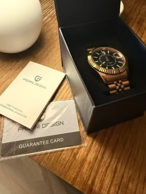 Guldfärgad klocka från Pagani Design - Stilren guldfärgad klocka från Pagani i ett lyxigare format. en elegant look för dig som vill sticka ut i vardagen! Allt extra finns med certifiering och garanti kort finns! 