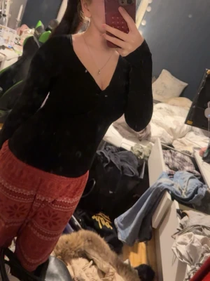 Svart v-ringad topp - Svart långärmad topp med v-ringning och figurnära passform. Perfekt att styla med olika underdelar för en enkel men snygg look. Materialet känns mjukt och stretchigt.