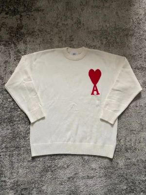 Vit Ami Paris tröja - Riktigt fet Ami tröja i vitt med röd logga på bröstet. Tröjan är storlek S och skicket är mycket bra, utan  några defekter. Perfekt för dig som söker en stilren look med en gnutta elegans. Hör gärna av dig vid minsta fundering så löser vi nåt!