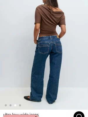 Blåa ultra low wide jeans - Säljer ett par blåa ultra low wide jeans med raka, vida ben och låg midja. Jeansen har klassiska bakfickor och kontrastsömmar. Perfekta för en avslappnad och trendig look.