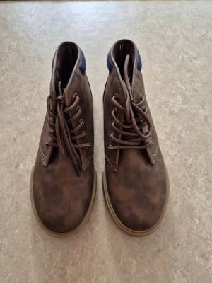 Kängor - Bruna kängor i skinnimitation (mockastil) med snörning och bekväm gummisula. Använda mycket lite, i fint skick.