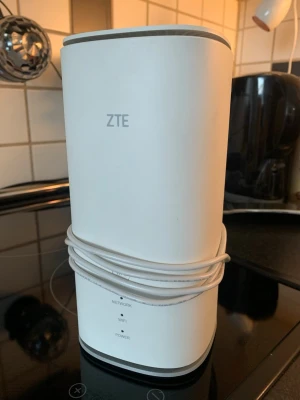 ZTE MC888 Ultra 5G-router - Säljer en vit ZTE MC888 Ultra 5G-router med rundade kanter och tillhörande nätadapter. Routern har indikatorlampor för nätverk, wifi och ström samt tydlig märkning undertill. Perfekt för snabbt internet hemma eller på kontoret. Nypris ca 3000kr