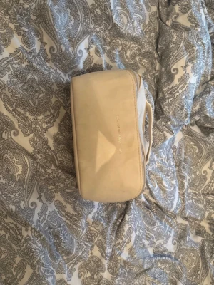 Beige necessär från Byredo - Snygg beige necessär från Byredo med dragkedja och praktiskt handtag. Insidan har flera fack för smidig organisering av dina grejer. Perfekt för att hålla koll på smink eller småprylar när du är på språng.