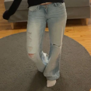 Ljusblåa lösa jeans med slitningar - Säljer ett par ljusblåa straight/baggy jeans med slitningar på låret och knät. Jeansen har låg midja. De är från Gina i storlek 164.