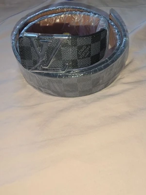 rutigt bälte svart/grå - Snyggt bälte i rutigt mönster och svart och grått. Perfekt accessoar för att lyfta din outfit.