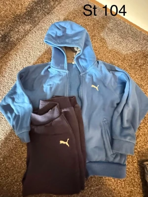 Blå hoodie från Puma med dragkedja - Säljer en blå hoodie från Puma med dragkedja och huva. Hoodien har ribbade muddar vid ärmslut och nederkant samt Puma-logga på bröstet. Perfekt för en sportig och avslappnad stil.