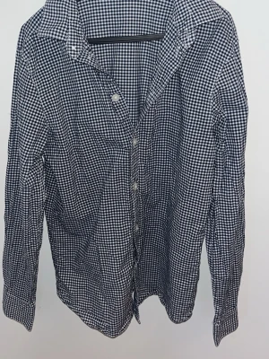 Rutig skjorta från H&M i blåvitt - Klassisk rutig skjorta från H&M i blått och vitt. Skjortan har långa ärmar, knappar framtill och en tidlös krage. Tillverkad i mjuk bomull som känns skön mot huden. Perfekt för dig som gillar en clean och enkel stil.