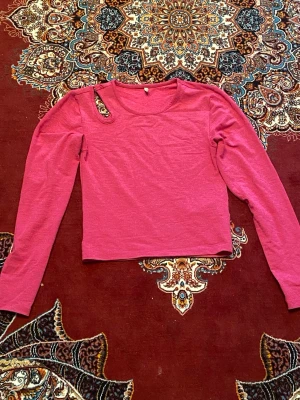 Rosa croppad långärmad topp - En enkel och snygg rosa croppad topp med långa ärmar och rund halsringning. Toppen har en clean look utan mönster eller tryck och är tillverkad i ett mjukt material som känns skönt mot huden. Perfekt att matcha med höga jeans eller kjol.