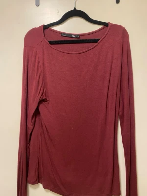 Mörkröd långärmad topp från Lager157 - En enkel och stilren mörkröd långärmad topp med rund halsringning. Perfekt att matcha med jeans eller kjol för en avslappnad look. Tillverkad i mjukt material som känns skönt mot huden.