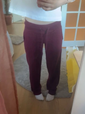 Vinröda mjukisbyxor med dragsko - Mysiga vinröda mjukisbyxor med resår och dragsko i midjan. Byxorna har raka ben och sidofickor, perfekta för chill dagar hemma. Materialet ser ut att vara mjukt och bekvämt, troligen bomull eller bomullsblandning. Älskar passformen på byxorna men använder ej💓💓(lite noppriga men man tänker inte på de)🤗🤗