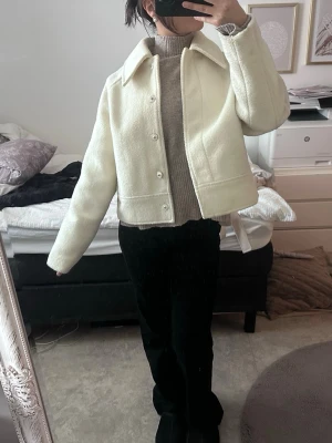 Beige teddyjacka med krage - Säljer en beige teddyjacka med klassisk krage och knäppning framtill. Jackan har en rak, något boxig passform och är perfekt för dig som gillar en stilren look. Materialet är mjukt och fluffigt, vilket gör den både snygg och bekväm.