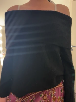 Svart off shoulder stickad tröja - Trendig svart stickad tröja med off shoulder-design och långa ärmar. Perfekt för dig som gillar en avslappnad men ändå snygg stil. Mjuk och stretchig kvalitet som sitter skönt på kroppen.