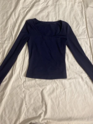 Mörkblå långärmad topp - En stilren mörkblå långärmad topp med rundad urringning. Toppen har en slim passform och är tillverkad i ett mjukt och stretchigt material. 