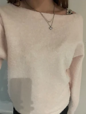 Ljusrosa fluffig stickad tröja -  ljusrosa stickad tröja med fluffig textur och avslappnad passform. Tröjan är oneshoulder och har långa ärmar, perfekt för lager-på-lager och en chill look.