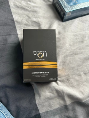 Emporio Armani Stronger With You Intensely - Emporio Armani Stronger With You Intensely är en herrparfym i en elegant, fyrkantig glasflaska med mörkbrun vätska och silverfärgad kork. Förpackningen är svart med guldiga detaljer och text. Flaskan rymmer 100 ml eau de parfum.