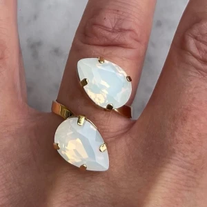 Pear ring white Opal  - Dubbel Pear Ring, i guldpläterad mässing med kristaller. Pear 14mm kristaller. Färg White Opal. Ställbar storlek. De sista bilderna visar andra färger och modeller som finns i lager. Jag skickar endast spårbart, samfraktar. Fast pris. Besök gärna mina övriga annonser.  Till mina smycken använder jag kristaller från Preciosa, Aurora och Swarowski.