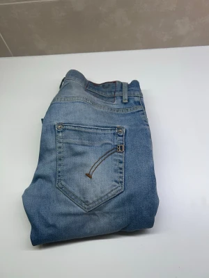 Dondup jeans - Snygga ljusblå jeans med klassisk femficksdesign och cool broderad detalj på bakfickan. Jeansen är tillverkade i Italien och har en avslappnad passform. Perfekta för en trendig och avslappnad stil.
