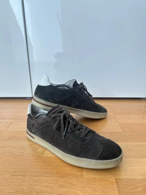 Loro Piana mörkbruna sneakers i mocka - Snygga mörkbruna sneakers från Loro Piana i mjuk mocka med vita detaljer vid hälen. 70s walk, heter numera tennis walk. Box samt dustbag. Skriv vid fler frågor!