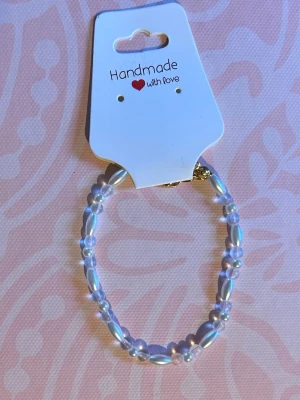 Pärlarmband med ovala pärlor - Snyggt handgjort armband med vita ovala och runda pärlor i skimrande finish. Armbandet har ett elastiskt band och passar de flesta handleder. Perfekt accessoar för att lyfta din outfit med en elegant touch.
