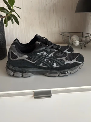Acics gel nyc svart och grå - Snygga sneakers från Asics i svart och grått. INGEN BOX! Dem är äkta och köpta från deras hemsida men jag slängde boxen för ett tag sedan. storlek 44,5 då passformen är väldigt liten då jag egentligen har storlek 43. Använda cirka 3 gånger och inga tecken på användning förutom lite smuts på botten som kan tvättas bort om önskat.
