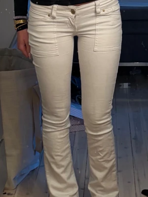 Vita bootcut jeans med guldknappar - Snygga vita bootcut jeans med framfickor och bakfickor med lock och guldiga knappar. Jeansen har låg midja och tight passform upptill som släpper ut vid benen. Perfekta för dig som gillar vita lågmidjade jeans❤️