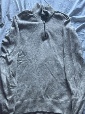 Beige stickad halvzip från Kappahl - Stickad beige tröja från Kappahl med halvzip och hög krage. Tröjan har långa ärmar och ribbade muddar vid ärmslut och nederkant. Perfekt för lager-på-lager och enkel att matcha med jeans. 