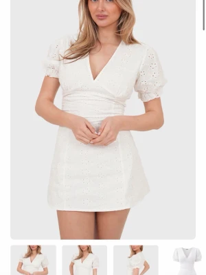 Vit kort klänning med prislapp kvar - Helt ny!! Superfin vit kort klänning med v-ringning, puffärmar och broderade blommönster.