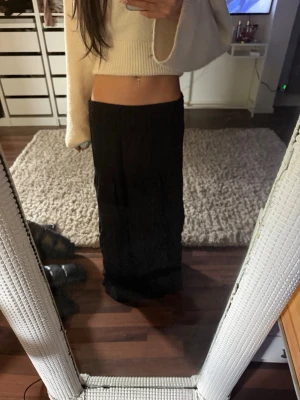 Svart långkjol med resårmidja - Säljer en svart långkjol med resår i midjan. Kjolen har en flowy och luftig passform som ger en avslappnad vibe. Perfekt att styla med en croppad tröja eller linne. Materialet känns lätt och bekvämt, perfekt för varmare dagar.
