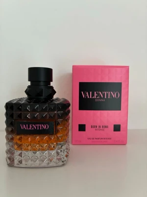 Valentino Donna Born In Roma Intense - Lyxig parfym från Valentino, Donna Born In Roma Intense. Flaskan är fyrkantig med nitar i glas, svart och transparent design samt rosa detaljer. Parfymen kommer i en snygg rosa kartong med svarta inslag. Perfekt för dig som gillar exklusiva dofter.