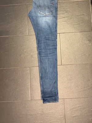 Replay jeans - Snygga blå slim fit jeans med klassisk femficksdesign och lätt slitning på låren. Jeansen har normal midja och smala ben, perfekta för en trendig och avslappnad stil. Materialet är mjukt och stretchigt för extra komfort. Lappen där bak saknas men övrigt är de i hyfsat skick.