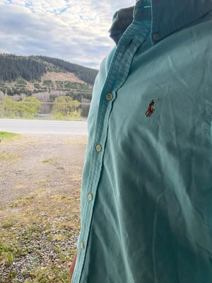 Ljusblå skjorta från Ralph Lauren - Säljer denna ralph lauren skjorta då den inte passar. Inga skador eller fläckar på denna otroliga skjorta! Jag skulle varmt rekommendera denna till sommaren och våren!☀️ Denna är i en blå färg som kan stylas till alla klädstilar! Strl: L 160-170. Hör gärna av dig vid frågor samt Pris kan diskuteras!🥰