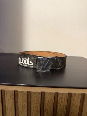 Bälte  - Snyggt brunt bälte . Bältet har tryckt vit text och är gjort i skinn med en lyxig känsla. Perfekt accessoar för att lyfta din outfit.