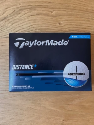 TaylorMade Distance+ golfbollar - TaylorMade Distance+ golfbollar i vit färg med rund form. Bollarna är tillverkade i slitstarkt material och har en plus alignment aid för bättre riktning. Perfekta för dig som vill ha extra längd på golfbanan.