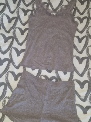 Ribbat set - Mysigt grått set med linne och shorts i ribbat material. Linnet har smala axelband och spetskant upptill, medan shortsen är enkla och bekväma. Perfekt för att chilla hemma eller som nattplagg. Enbart testat