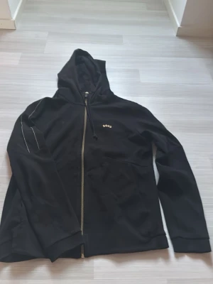 Svart zip up hoodie - En svart zip hoodie med guld mönster 