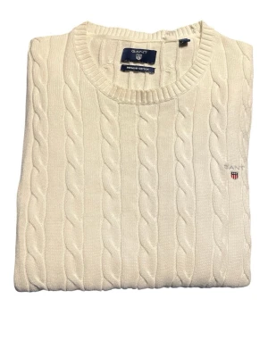 GANT kabelstickad tröja vit, stl M - Klassisk kabelstickad tröja från GANT i offwhite/vit färg. Storlek M. Stilren modell med broderad logo på bröstet. Passar perfekt till preppy/old money/clean stil. Bra skick med normala tecken på användning. Mindre missfärgning vid krage finns. Syns på sista bilden. Rate 8,5/10