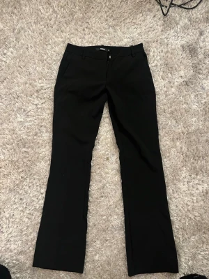 Svarta kostymbyxor bootcut från bikbok - Snygga svarta kostymbyxor med bootcut passform och hällor för skärp. Klassisk design med raka ben och diskreta fickor framtill. Perfekta för en stilren look. Säljer pga för korta.