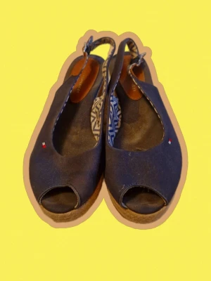Wedges Tommy Hilfiger - Snygga blå sandaler med öppen tå och kilklack från Tommy Hilfiger. Ovandel i tyg, sula i repimitation och justerbar rem med spänne. Små broderade loggor på ovandelen och innersula med grafiskt mönster. Perfekta för sommaren!