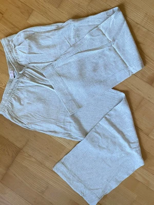 Beiga vida linnebyxor med resår - Snygga och luftiga linnebyxor i beige med breda ben och resår i midjan. Perfekta för en avslappnad och trendig stil. Gjorda i ett lätt och svalt linnematerial som passar perfekt till sommaren.