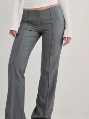 Grå kostymbyxor med pressveck - Snygga grå kostymbyxor med raka ben och markerade pressveck framtill. Byxorna har hög midja och en klassisk, stilren look som passar till många olika outfits. Tillverkade i ett mjukt och följsamt material för en bekväm känsla.