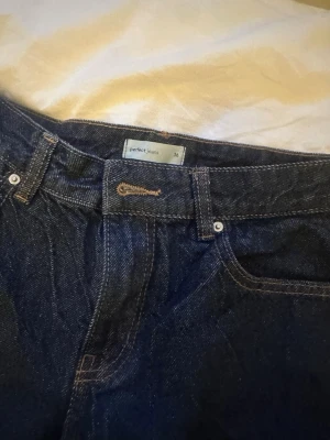 Mörkblå raka jeans från Gina Tricot - Säljer ett par mörkblå lågmidjade jeans från Gina Tricot i modellen 'perfect jeans'. Jeansen har raka ben, klassisk femficksdesign och tydliga kontrastsömmar. Perfekta till en avslappnad och trendig look. Materialet är kraftig denim i bomull. 