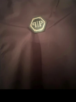 Mörklila vindjacka från Philip plain  - Snygg mörklila vindjacka från philip plain med kraftig dragkedja och metall-dragflärp. Jackan har hög krage och är tillverkad i ett tunt, vindtätt material som passar perfekt för blåsiga dagar. Storlek S men passar till m är lite stor i storleken.pris kan diskuteras mycket 