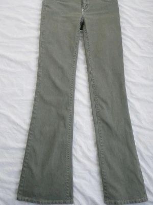 gröna boot cut nelly - Säljer ett par gröna jeans med bootcut-modell och klassisk femficksdesign. Jeansen har dekorativa sömmar på bakfickorna och är tillverkade i ett mjukt denimtyg. low waist