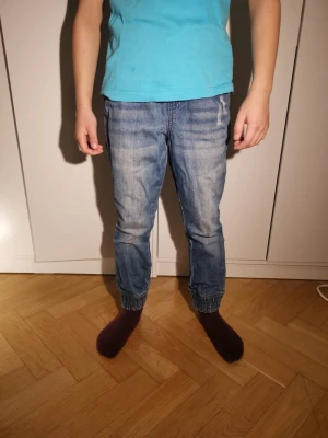 2 Jeans stl 128 Blå och grå👖 - Säljer ett par ljusblå och ett par grå jeans med resår i benslut och midja.👖✨ Jeansen har en avslappnad passform, klassiska fem fickor och är tillverkade i denim med tvättad look.💫 Byxorna har vita knytsnören och märket är John Baner. Perfekta för en chill och bekväm stil.💯                                       (Båda för 99kr)