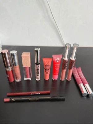 Mix av läppglans och läppennor - Säljer ett kit med flera läppglans och läppennor i olika nyanser av nude, rosa och rött. Märken som L'Oréal, W7, P.S. och Maybelline. Innehåller både flytande läppglans, gloss i tub och pennor. Perfekt för dig som vill variera din look med både matta och glansiga finishar.