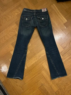 True Religion bootcut jeans blå - KONTAKTA INNAN NI KÖPER! 💕Mörk blå bootcut jeans från True Religion med kontrastsömmar och snygga fickdetaljer. Dom ser nt bootcut ut när jag har på dem men de beror på att jag e väldigt lång. Jeansen har en lätt tvättad look och är tillverkade i denim. Så sjukt snygga men har inte kunnat ha dom till användning. Nypris var 699 kr 
