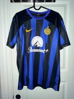 Inter Milan matchtröja Lautaro #10 - Snygg Inter Milan matchtröja i svart och blått med gula detaljer. Framsidan har Nike-logga, klubbmärke och Paramount+ sponsortryck. Baksidan har LAUTARO och nummer 10 tryckt i vitt. Perfekt för fotbollsfans!