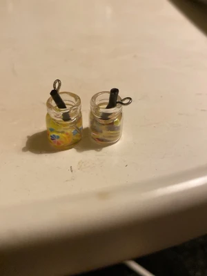 Drink örhängen - Unika örhängen som ser ut som små glas med lemonad, dekorerade med färgglada citronskivor och ett svart sugrör. Perfekta för dig som gillar roliga och kreativa accessoarer. Tillverkade i plast och metall.