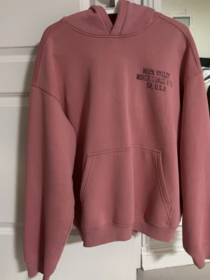 Flamingorosa hoodie  - En flamongorosa hoodie med Napa Valley tryck i lite oversized passform (främst armarna). Storlek L men kan funka som en stor M också. Använd några få gånger. 