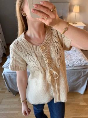 Beige stickad topp med knyte i midjan - storlek xs/s - Säljer denna super söta toppen som är stickad. Den är i storlek XS/S men skulle även tro att den passar en M. Färgen är beige och passar perfekt till våren. Jag har köpt den secondhand men den är i jättefint skick utan defekter🌸  Hör gärna av dig vid frågor💗